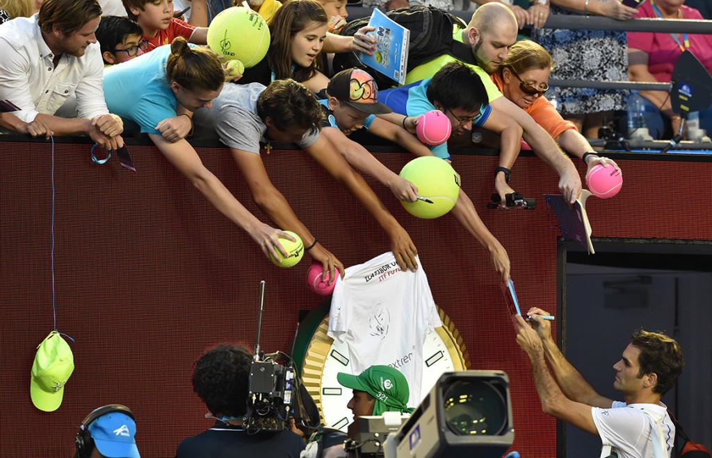 El suizo Roger Federer (D) firma autógrafos después de vencer a Nikoloz Basilashvili. Foto AFP/S. Khan
