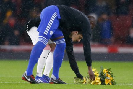 El mediocampista alemán Mesut Ozil (I), del Arsenal, y Sol Bamba (D), defensor marfileño del Cardiff City, colocan un par de ramos de narcisos en honor al desaparecido jugador argentino Emiliano Sala,