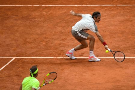 Roger Federer trata de devolver una bola a un Rafael Nadal que aguarda en la red