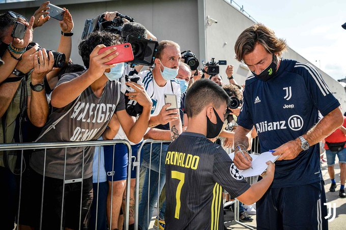 Andrea Pirlo complace a un joven fan con su firma ante la mirada de los medios de comunicación. Foto Juventus 